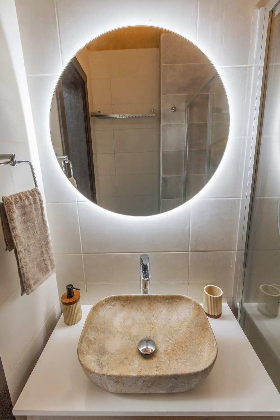 Stone vessel basin under a backlit mirror